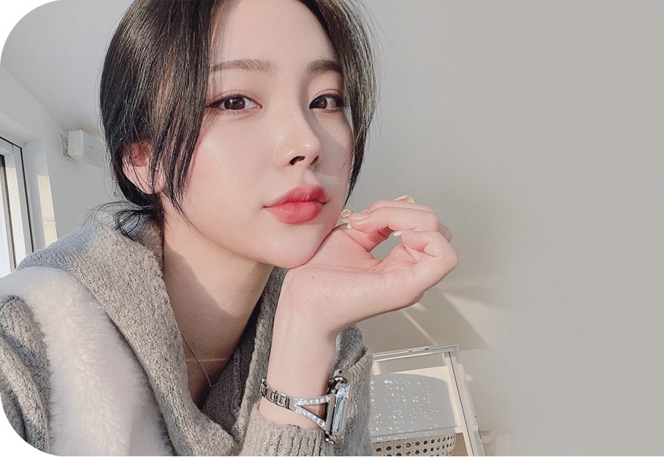 턱에 손을 괸 단발 여성 모델(회색 니트, 밝은 실내)